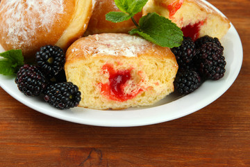 Tasty donuts with berries on wooden table