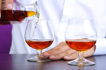 Bartender is pouring cognac into glass