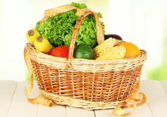 Fresh vegetables in wicker basket on table on light background