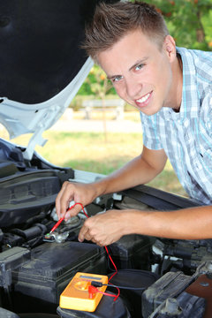 Young driver uses multimeter voltmeter to check voltage level