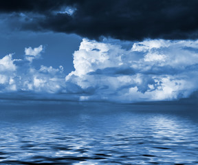 Sky with clouds reflected in water surface. Blue toned image.