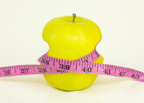 Pulling Tight Measuring Tape On A Green Apple