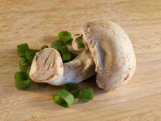 Champignon on wooden board with green onion