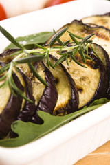 Grilled eggplant slices on a plate with fresh rosemary