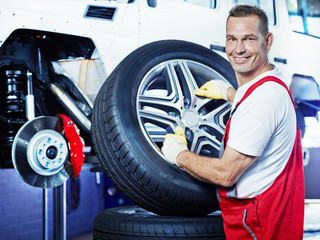 Motor mechanic changes a tyre with new alu rim