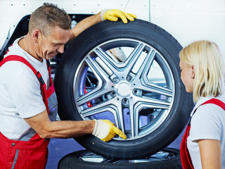 Car mechanic explains tyre changing to a trainee