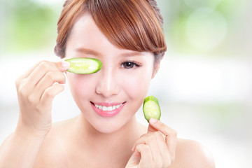 beautiful woman holding cucumber slices on face