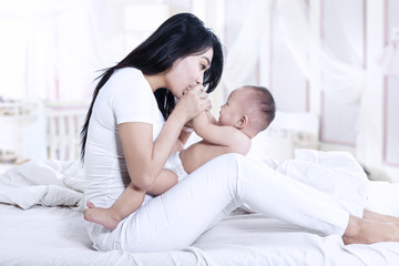 Beautiful mother kissing baby at home