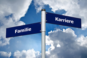 Straßenschild vor bewölktem Himmel welches die Entscheidung zwischen 'Familie' und 'Karriere' symbolisiert