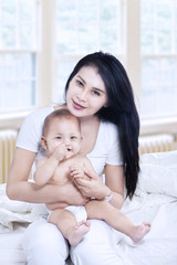Fototapeta na wymiar Asian mother and baby sitting in living room