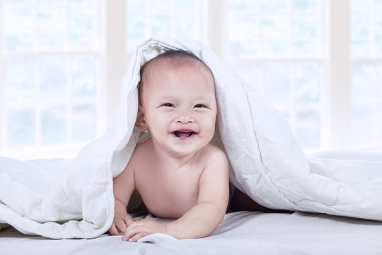Happy baby under blanket at home