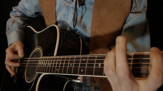 male hands play on acoustic guitar