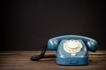 Retro rotary telephone on table against black background