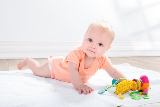 baby girl  with toy, lying on the floor