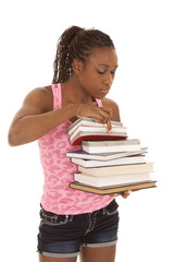woman pink tank look through stack of books
