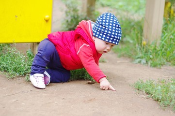 baby points something sitting on the ground on playground