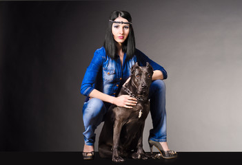 Beautiful woman in jeans clothes sitting next to pitbull