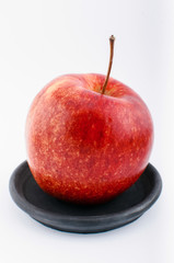 Red apple on black saucer.