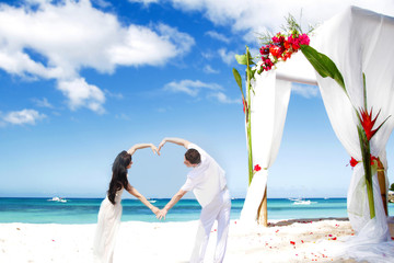 loving couple on wedding day on tropical beach near bamboo arch
