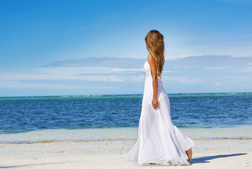 Fototapeta na wymiar young beautiful woman in wedding dress on tropical beach and wat