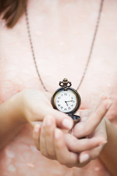 Portrait of young attractive woman with clock on chain