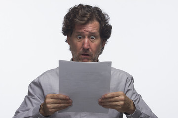 Business man reading report looking shocked, horizontal