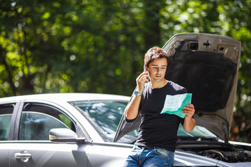 Handsome young man calling for assistance with his car broken
