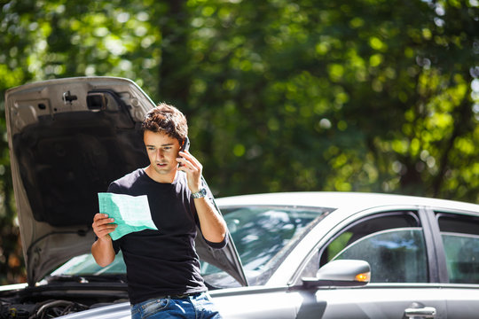 Handsome young man calling for assistance with his car broken