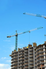 Crane and building construction site against blue sky