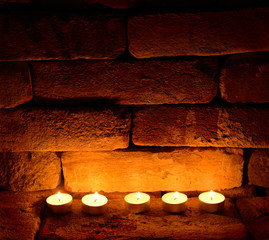 Five tea candles on brick wall background