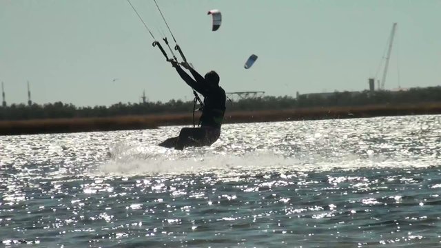 Kiteboarding, kitesurfing, action sport kiteboarding harnesses power of summer wind with a large controllable power kite to be propelled across water