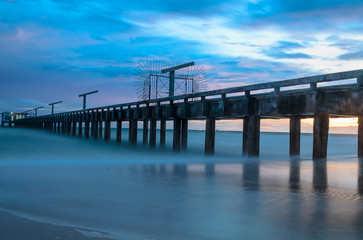 Fototapeta premium Bridge to the sea with sunset bihind
