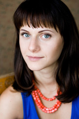 Portrait of a beautiful young brunette with red beads