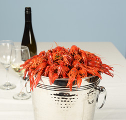 pail full of river lobster with wine and glasses