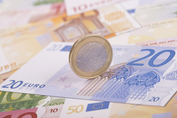 Economy concept with One Euro coin on Euro banknotes