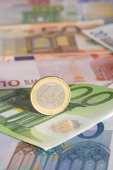 Economy concept with One Euro coin on Euro banknotes