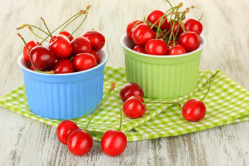 Cherry berries in bowls on wooden table close up