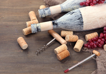 Fototapeta na wymiar Old bottles of wine, grapes and corks on wooden background