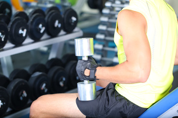 Fototapeta premium Guy with dumbbells on gym background close-up
