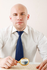 A businessman reading a newspaper with magnifier