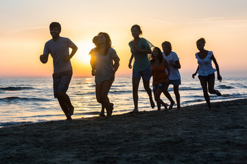 Group of People Running on the Beach at Sunset