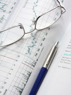 Financial charts, a pen and glasses