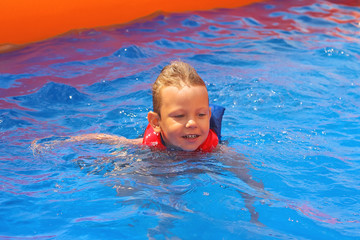 Fototapeta na wymiar Enthusiastic kid in vest at the pool water park