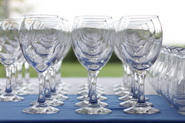 several rows of wine glasses set outdoors on the table