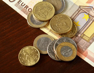 Money: euro coins and bills close up isolated on wood background
