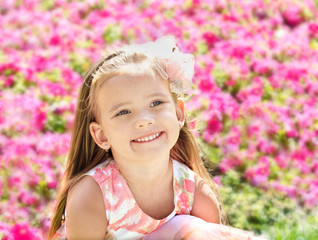 Outdoor portrait of cute little girl near the flowers