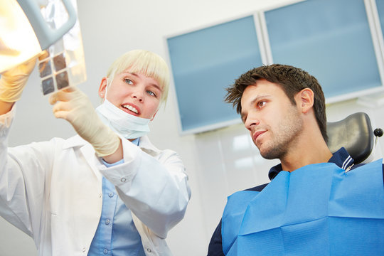 Zahnarzt zeigt Patient Karies auf Röntgenbild