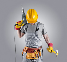 builder in a helmet with a hammer and a drill