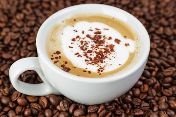 cappucino in cup on coffee beans