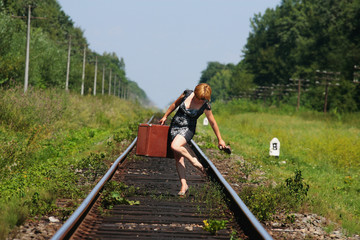 girl on the railroad track with suitcase